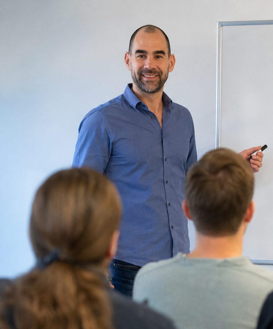 Marco erklärt am Whiteboard vor einem kleinen Team